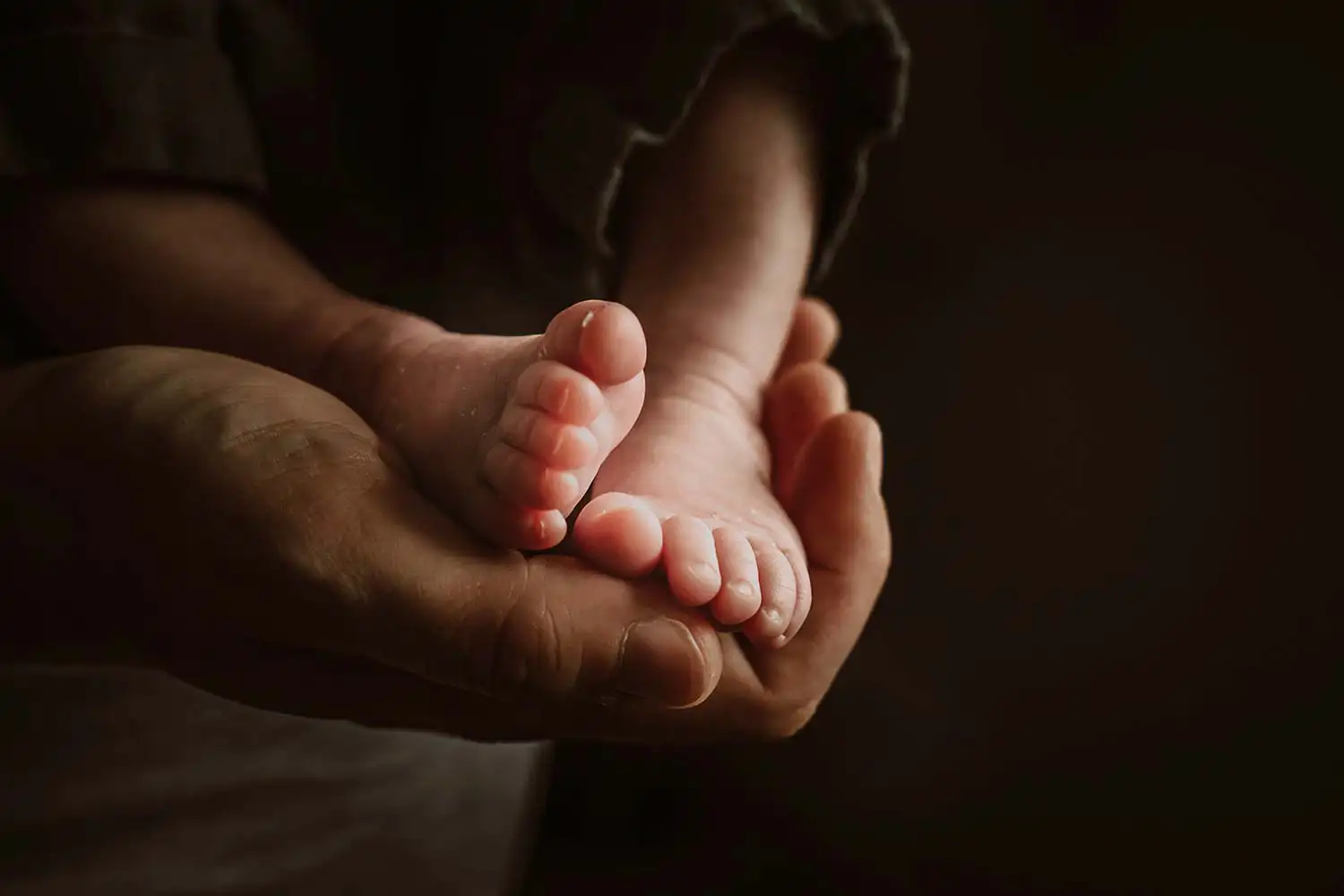 wunderschönes Detail im Foto von den kleinen Babyfüßen in der Hand des Papas 