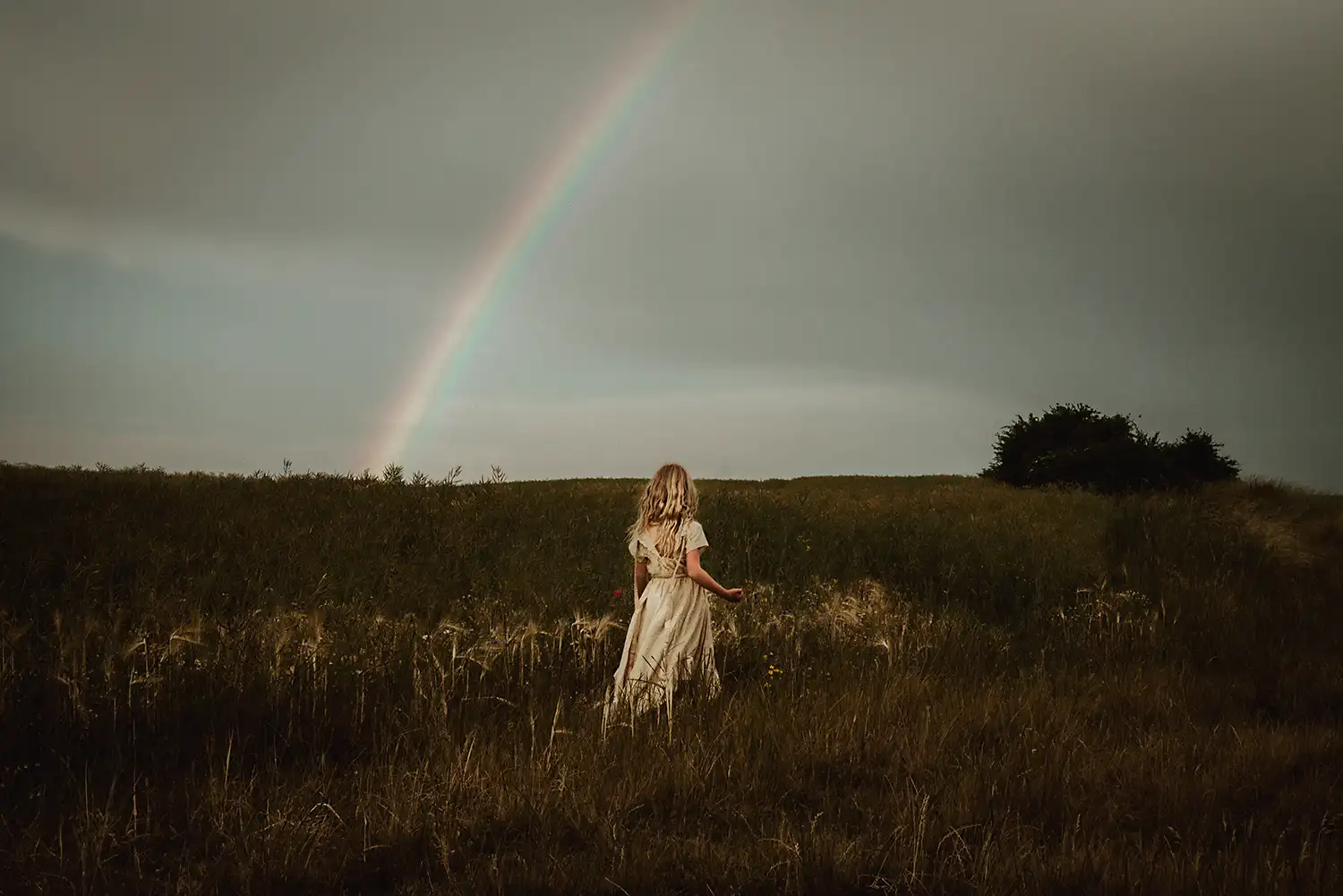 Mädchen im wunderschönen Boho Style Kleid vor dem Regenbogen im warmen Licht