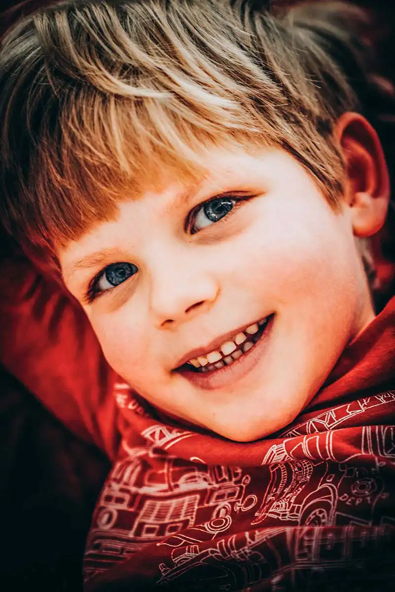 Portait des fröhlichen Jungen in rottönen bei der Familienfotosession