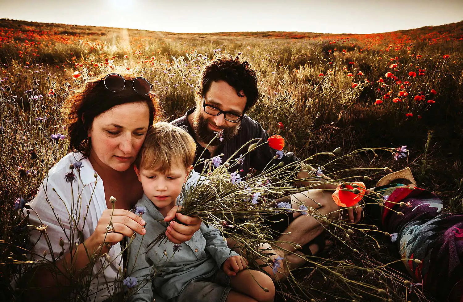 Das berühmte Abschlussbild eines Familien Fotoshootign zeigt die Famile zusammen im sommerlichen Kornfeld sitzend