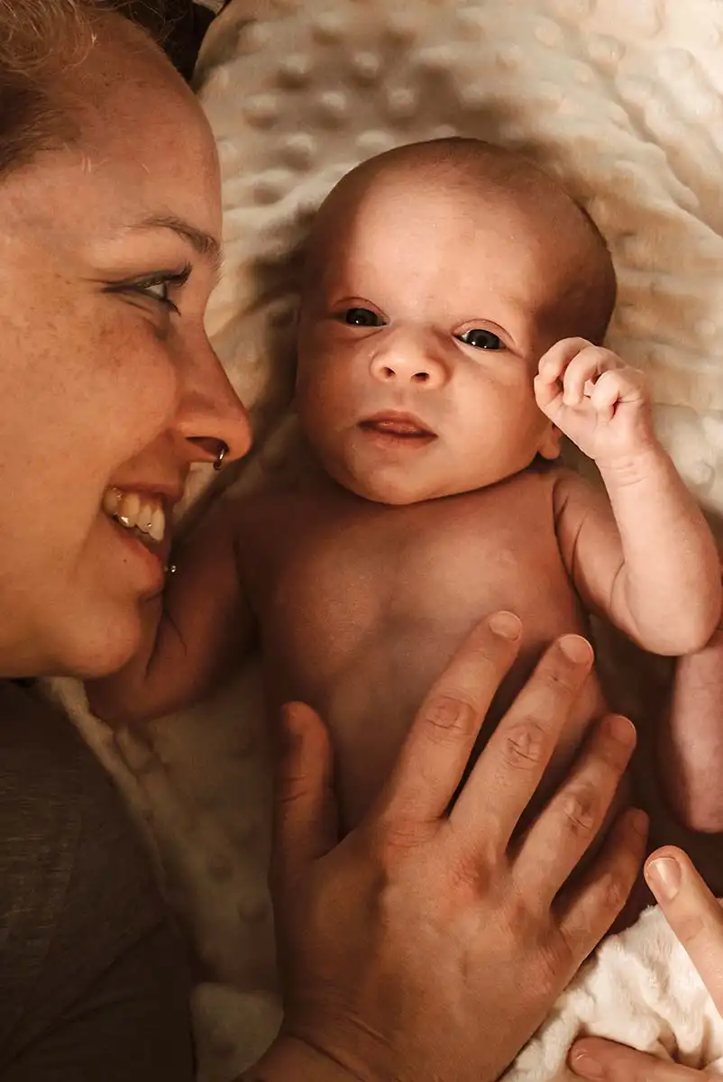 Ein glückliches Newborn Baby ist auch ein grinsende Mama beim Foto zu Hause