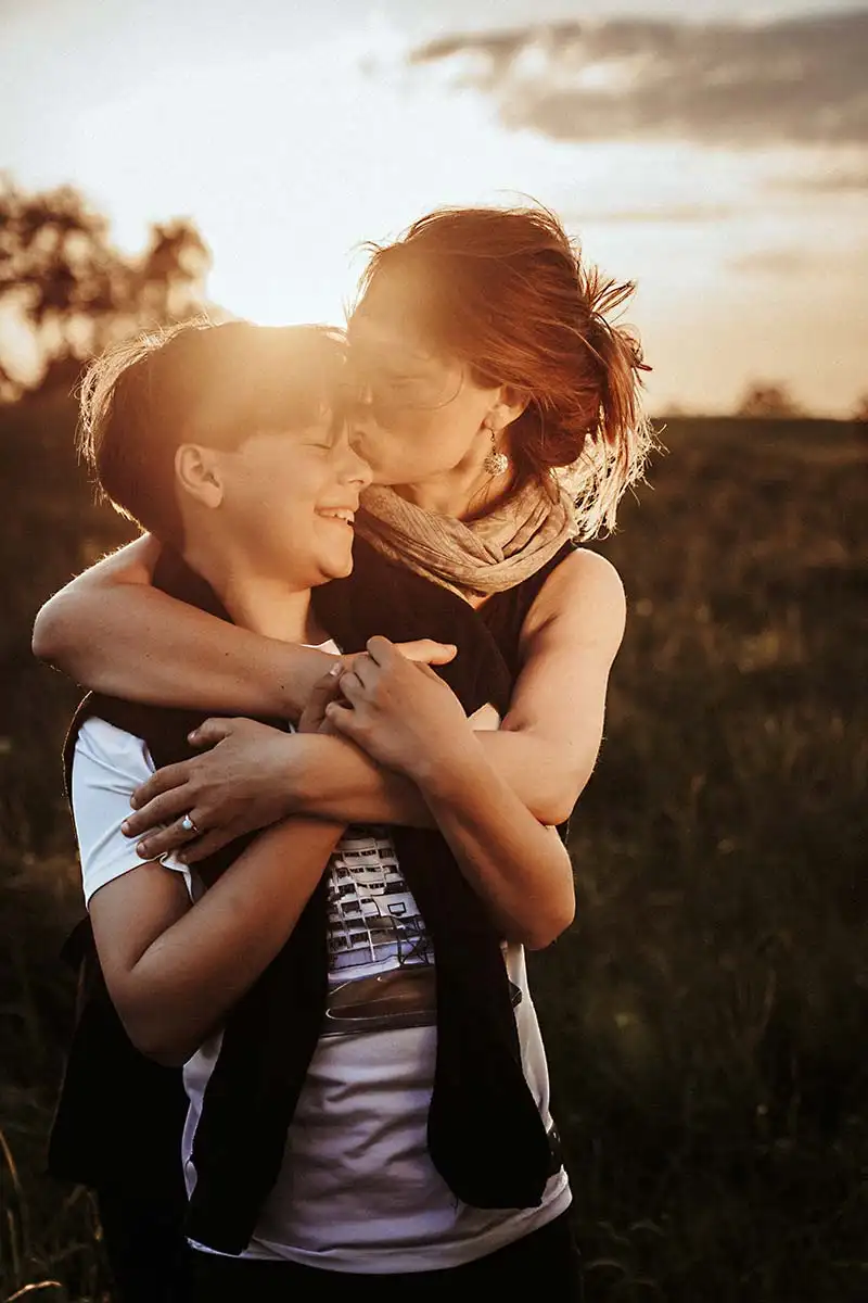 zärtlicher Kuss von Mama bei Fotografie Shooting im Sonnenuntergang