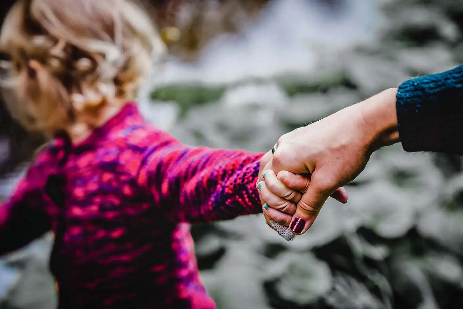 sie hält ihre Tocher an der Hand von der Familienfotografin festgehalten