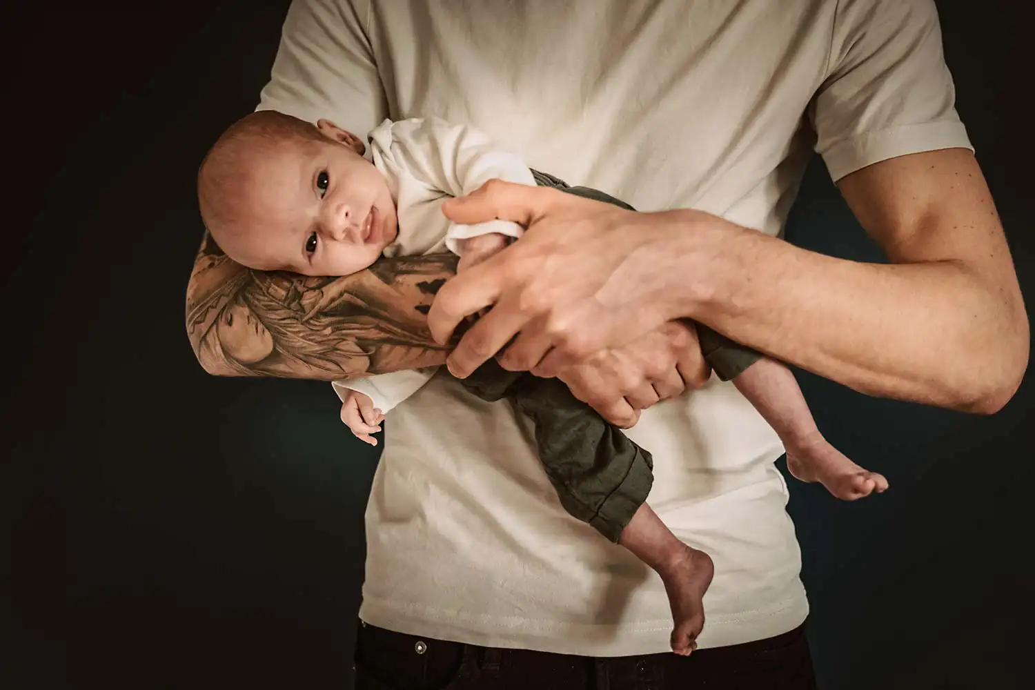 Vater mit einem der Zwillings Mädchen auf dem Arm mittenim Newborn Shooting